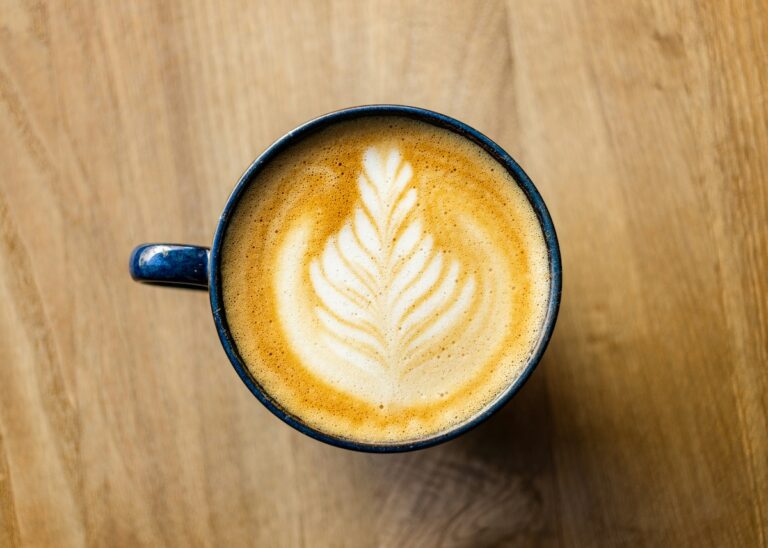 Photo d'une tasse de café, au lait avec une feuille dessinée dans la mousse